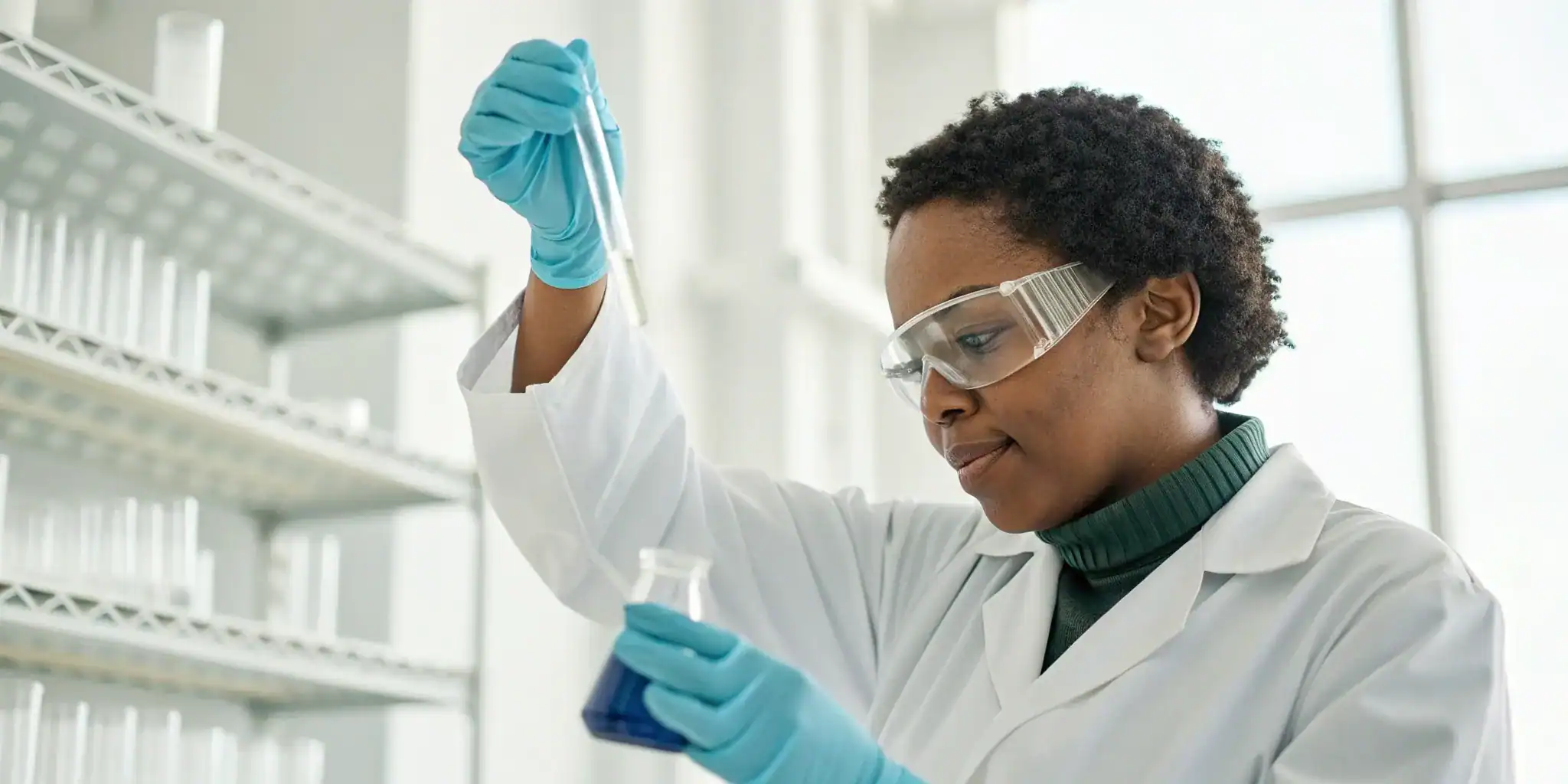 A lab worker in full PPE who needs bloodborne pathogens training handles samples.