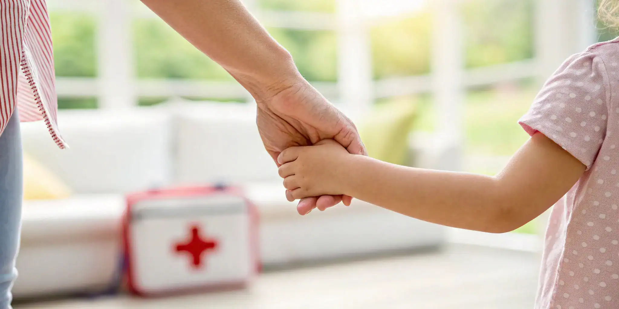 Adult and child holding hands with a first aid kit for pediatric first aid and CPR online training.