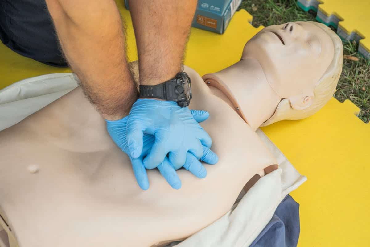 An instructor demonstrates CPR chest compressions on a training manikin during a certification renewal class.